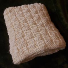 a white knitted blanket laying on top of a black surface