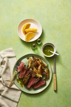 a steak and potatoes dish on a plate next to a bowl of green olive sauce