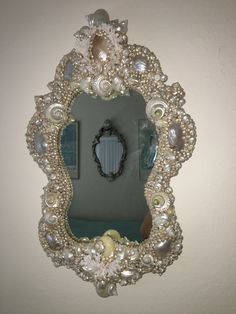 a mirror that is on the wall with pearls and other things around it in front of a white wall