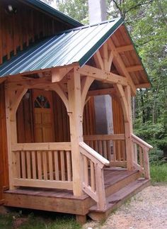 a small wooden cabin in the woods with porches and steps leading up to it