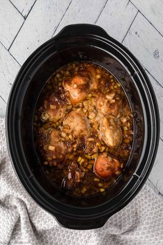 a crock pot filled with chicken and beans on top of a white table cloth