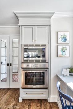 a kitchen with white cabinets and stainless steel oven in the center, along with hardwood flooring