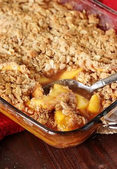 a casserole dish filled with fruit and crumbled toppings on a wooden table