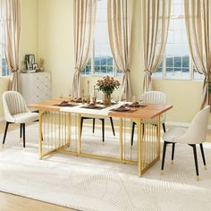 a dining room table and chairs in front of two windows with drapes on them