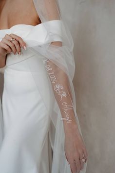 a woman wearing a wedding veil and holding her arm with the word happily written on it