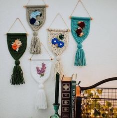 three wall hangings with flowers and tassels on them