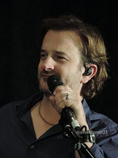 a man holding a microphone in his right hand and wearing earphones on his left