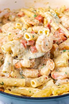 a pasta dish with shrimp and cheese in a blue bowl on top of a white table