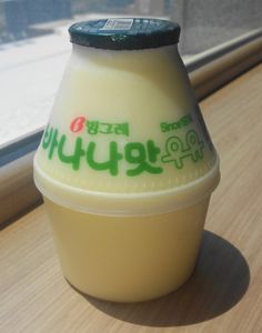 a bottle of yogurt sitting on top of a table next to a window