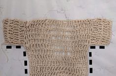 a piece of crocheted material on a white tablecloth with black squares around it