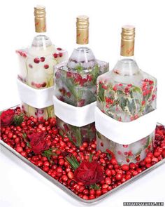 three wine bottles are wrapped in white ribbon and decorated with pomegranates