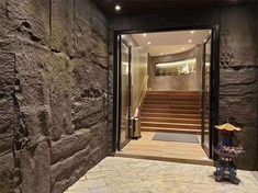 an entry way with stone walls and steps leading up to the second floor, which is lit by recessed lighting