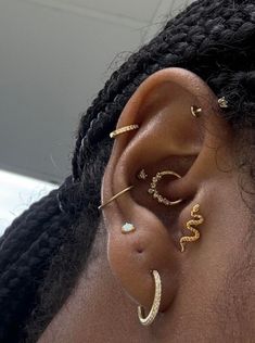 a close up of a person's ear with gold jewelry on top of it