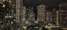 the city skyline is lit up at night with skyscrapers in the foreground and lights on