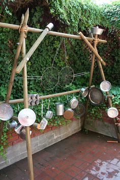 several pots and pans are arranged in an outdoor setting with plants growing on the wall