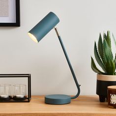 a desk lamp sitting on top of a wooden table next to a potted plant