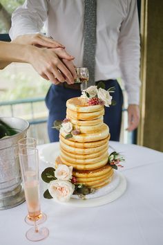 a man and woman standing next to a tall stack of pancakes on top of a table