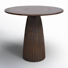 a round wooden table sitting on top of a white floor next to a metal object