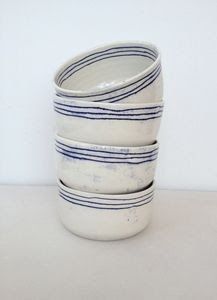 four white and blue striped bowls stacked on top of each other in front of a white wall