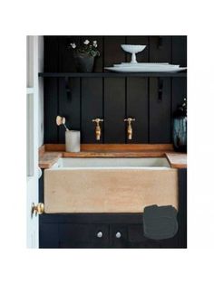 a kitchen sink with two faucets on the counter and black walls behind it