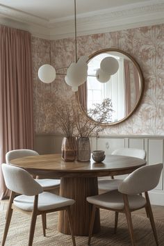 a dining room table with four chairs and a round mirror