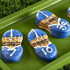 cookies decorated to look like footballs are sitting on a green tray in the grass