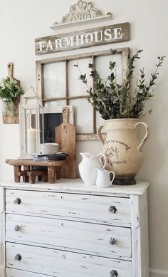 a white dresser with an old window and potted plants on it's top