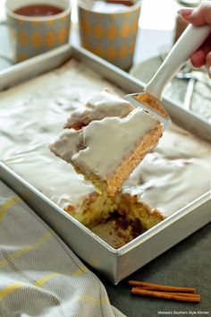 a person is holding a piece of cake in a pan with icing on it