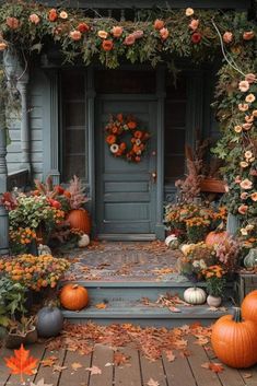 a front porch with pumpkins and flowers on the steps, surrounded by greenery