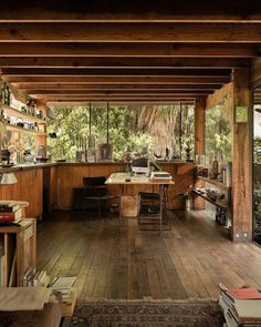 an open kitchen and dining area with wooden floors, wood ceilinging and large windows