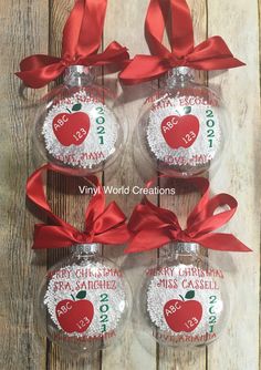 three glass ornaments with red ribbon on them and an apple in the middle one is personalized