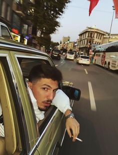 a man sitting in the passenger seat of a car with his hand on the window