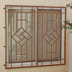 a window with an iron frame and decorative design on the side of a building next to a flower pot