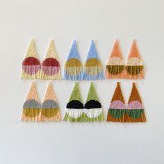 six different colored crochet earrings on a white surface