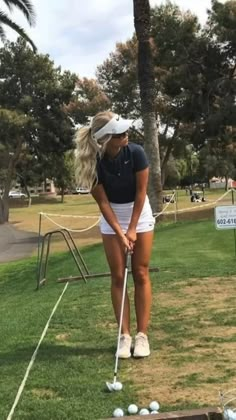 a woman is playing golf in the grass