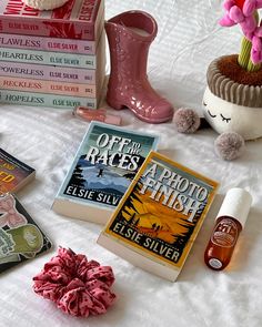 there are many books on the bed with pink flowers in vases next to them