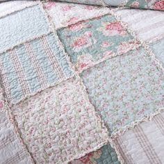 a quilted bed with pink and blue flowers on it