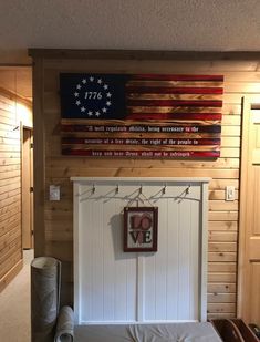 an american flag on the wall above a bed in a room with wood paneling