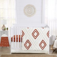 a white crib with a red and white quilt on it