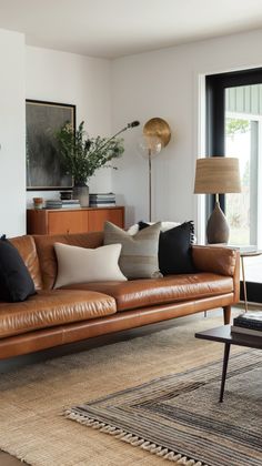 a living room filled with lots of furniture and pillows on top of a brown couch