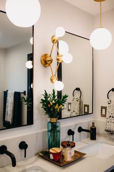 a bathroom sink with lights hanging above it and a mirror on the wall behind it