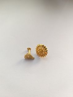 two gold earrings sitting on top of a white surface