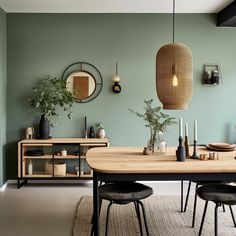 a dining room with green walls and wooden table surrounded by black chairs, vases and potted plants