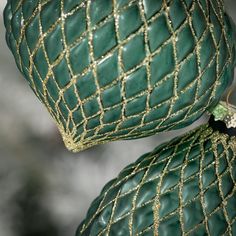 two green and gold christmas ornaments hanging from a tree ornament, one with an ornament on it's side