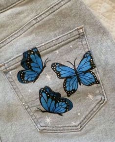 three blue butterflies sitting on the back of a pair of jeans