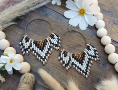 a pair of earrings sitting on top of a wooden table next to flowers and feathers