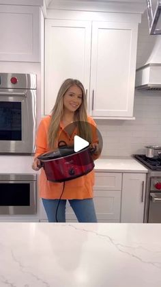 a woman standing in a kitchen holding a red bag