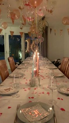 a table set for a birthday party with balloons and candles in the center, surrounded by confetti