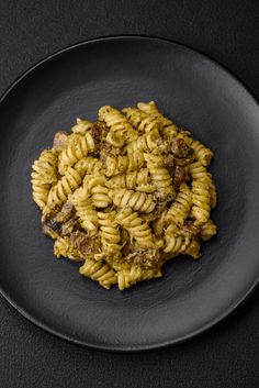 a black plate topped with pasta and meat