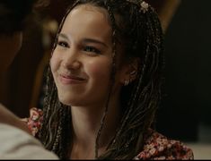 a woman with dreadlocks smiles at another person